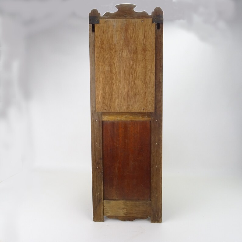 May include: A tall, wooden cabinet with a rectangular door and a smaller, rectangular door below it. The cabinet is made of dark wood with a light wood trim. The doors are closed and have a simple design.