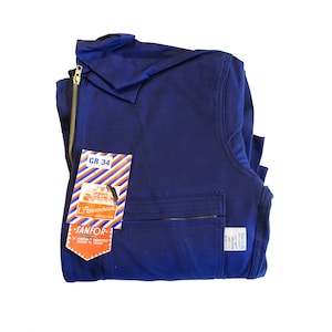 May include: A navy blue work jumpsuit with a zipper closure and a pocket on the front. The jumpsuit has a label that says "L'Ascenceur Construction" and "Janfor." The label also has the text "CR 34."