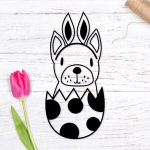 May include: Black and white line art illustration of a bunny rabbit peeking out of an egg with polka dots. The bunny has long ears and a cute face.