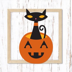 Puede incluir: Un gato negro con ojos amarillos se sienta dentro de una calabaza naranja sonriente. El gato est&aacute; asom&aacute;ndose por la parte superior de la calabaza.