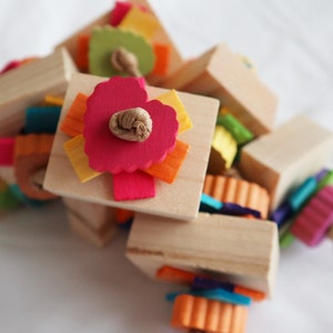 Puede incluir: Un juguete de madera con piezas de fieltro de colores y una cuerda anudada. El juguete está hecho de madera natural y tiene una variedad de texturas para que una mascota pueda explorar.