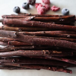 May include: A pile of thin, dark red wooden sticks, likely for crafts or pet chewing.