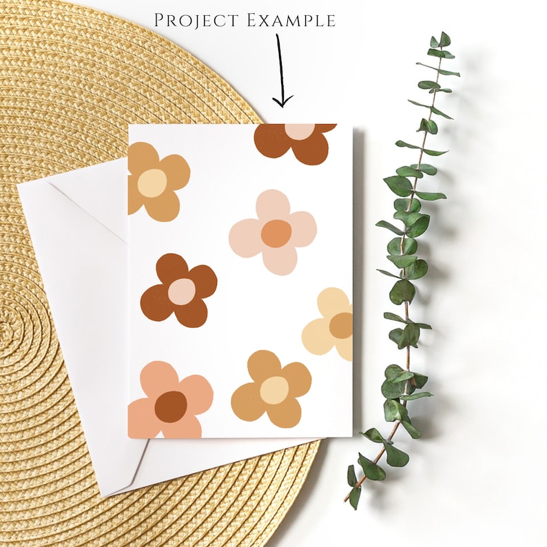 May include: A white card with a pattern of brown, pink, and orange flowers. The card is sitting on a woven straw mat.
