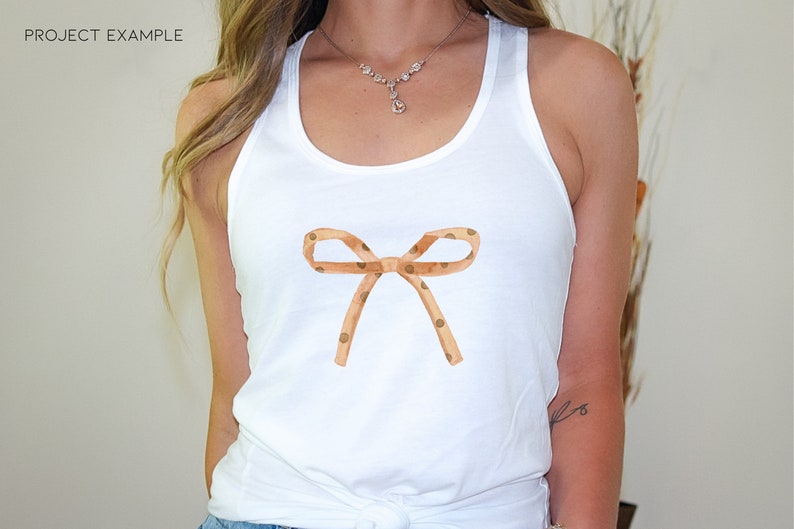 May include: White tank top with a brown and white polka dot bow on the front.