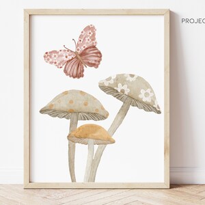 May include: A watercolor painting of three mushrooms with different colored tops and a pink butterfly flying above them. The mushrooms have white and brown polka dots and white flowers on the tops.