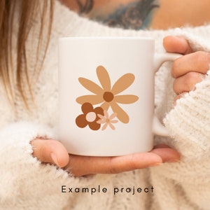 May include: White ceramic mug with a brown, pink, and orange floral design. The flowers are stylized and abstract.