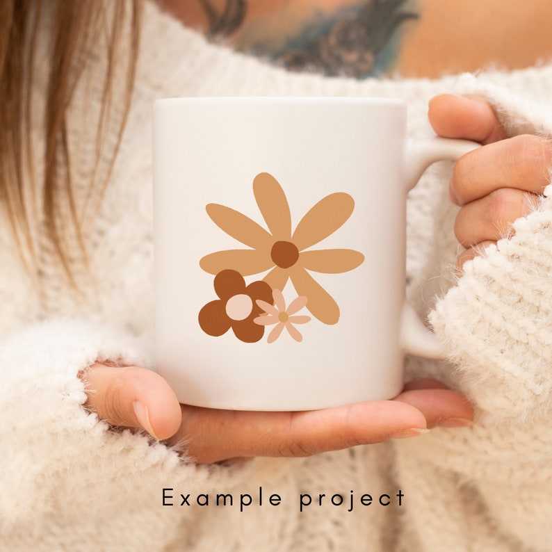 May include: White ceramic mug with a brown, pink, and orange floral design. The flowers are stylized and abstract.