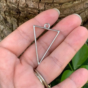 May include: Silver triangle pendant with a loop at the top. The pendant is a simple geometric shape with a smooth, polished finish.