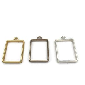 May include: Three metal rectangular frames with a loop at the top. The frames are gold, silver, and bronze.