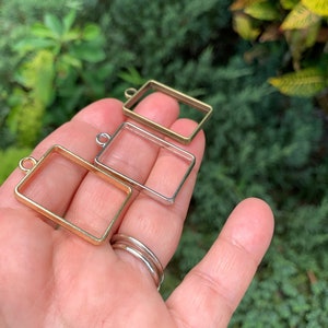 K&ouml;nnte beinhalten: Drei Metallbilderrahmen mit einer &Ouml;se oben zum Aufh&auml;ngen. Die Rahmen sind golden, silbern und bronzefarben.