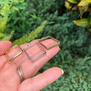 K&ouml;nnte beinhalten: Drei quadratische Metallrahmen in verschiedenen Gr&ouml;&szlig;en. Die Rahmen sind in Gold, Silber und Messing.