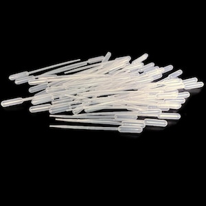 Puede incluir: Un conjunto de pipetas de plástico transparente, con extremos bulbosos y puntas finas. Las pipetas están dispersas sobre un fondo negro, lo que sugiere un entorno de laboratorio para la transferencia de líquidos.