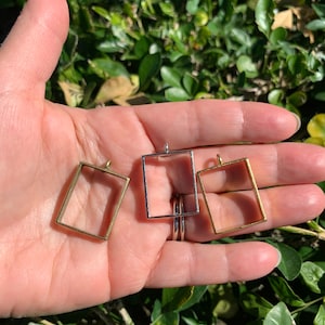 May include: Three metal picture frames in different sizes. The frames are silver, gold, and brass. The frames are all rectangular and have a simple design.