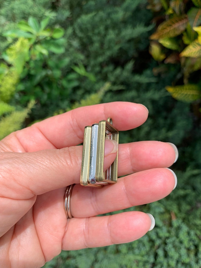 K&ouml;nnte beinhalten: Drei quadratische Metallrahmen, einer silber und zwei gold, &uuml;bereinander gestapelt. Die Rahmen sind daf&uuml;r ausgelegt, ein kleines Bild oder einen anderen Dekorationsgegenstand zu halten.