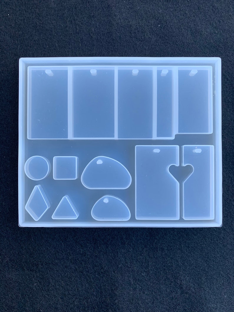 May include: Clear silicone mold with multiple shapes for resin casting. Includes rectangular, round, oval, heart, diamond, and triangle shapes. Also includes four rectangular molds with two holes each.