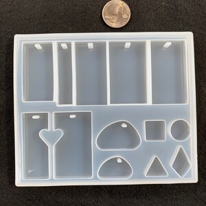 May include: Clear silicone mold with multiple shapes for resin casting. The mold includes six rectangular shapes with a hole at the top, a heart shape, a teardrop shape, a rounded rectangle, a square, a circle, a triangle, and a diamond shape.