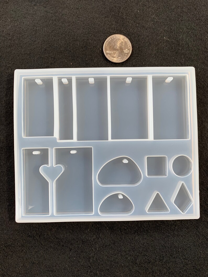 May include: Clear silicone mold with multiple shapes for resin casting. The mold includes six rectangular shapes with a hole at the top, a heart shape, a teardrop shape, a rounded rectangle, a square, a circle, a triangle, and a diamond shape.