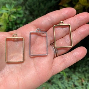 K&ouml;nnte beinhalten: Drei Metall-Anh&auml;nger-Rahmen in Gold, Silber und Bronze. Jeder Rahmen ist rechteckig mit einer kleinen Schlaufe oben zum Aufh&auml;ngen.