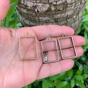 K&ouml;nnte beinhalten: Drei rechteckige Metallrahmen mit einer Schlaufe oben. Die Rahmen sind golden, silbern und bronzefarben.