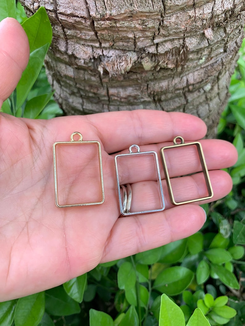 K&ouml;nnte beinhalten: Drei rechteckige Metallrahmen mit einer Schlaufe oben. Die Rahmen sind golden, silbern und bronzefarben.