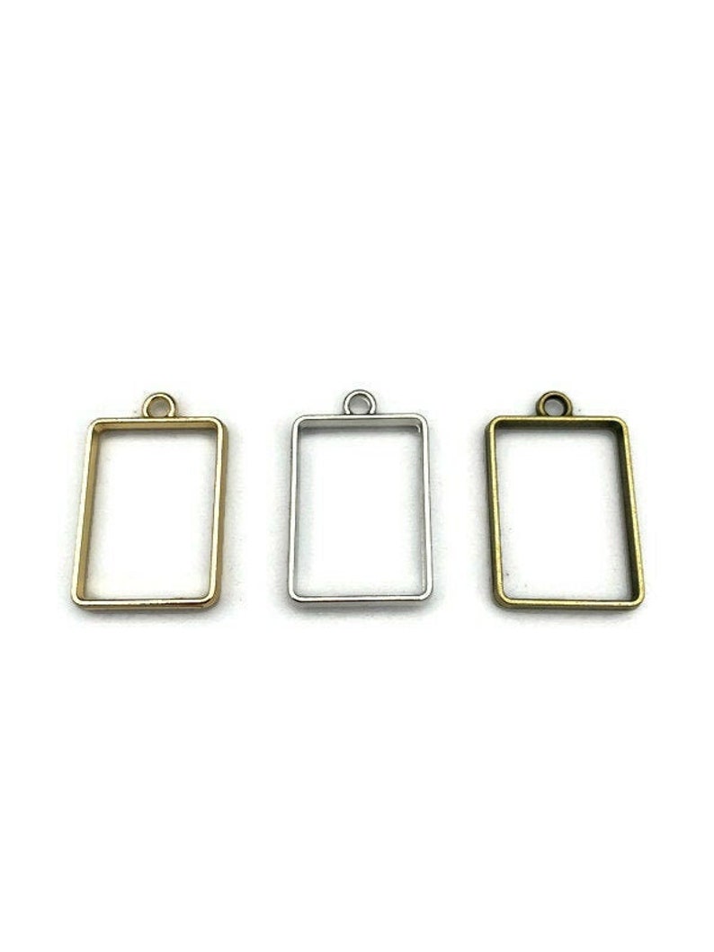 K&ouml;nnte beinhalten: Drei Metall-Anh&auml;nger-Rahmen in Gold, Silber und Bronze. Jeder Rahmen ist rechteckig mit abgerundeter Oberseite und einer Schlaufe zum Aufh&auml;ngen.