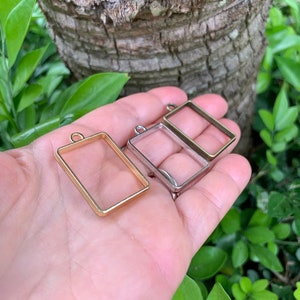 K&ouml;nnte beinhalten: Zwei rechteckige Metallrahmen f&uuml;r die Herstellung von Harzschmuck. Ein Rahmen ist golden und der andere ist silber.