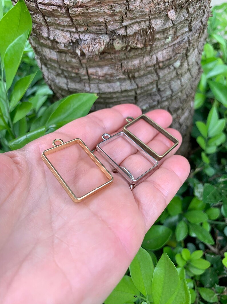 K&ouml;nnte beinhalten: Zwei rechteckige Metallrahmen f&uuml;r die Herstellung von Harzschmuck. Ein Rahmen ist golden und der andere ist silber.