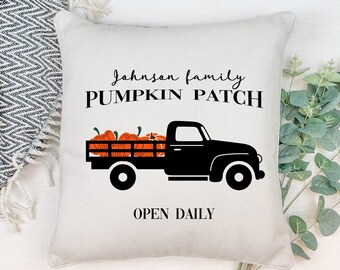 May include: A white pillow with black text that reads "Johnson family PUMPKIN PATCH OPEN DAILY". A black silhouette of a pickup truck with a bed full of orange pumpkins is in the center of the pillow.