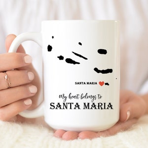 May include: White ceramic mug with a black outline of the islands of Santa Maria, a red heart, and the text "my heart belongs to SANTA MARIA".