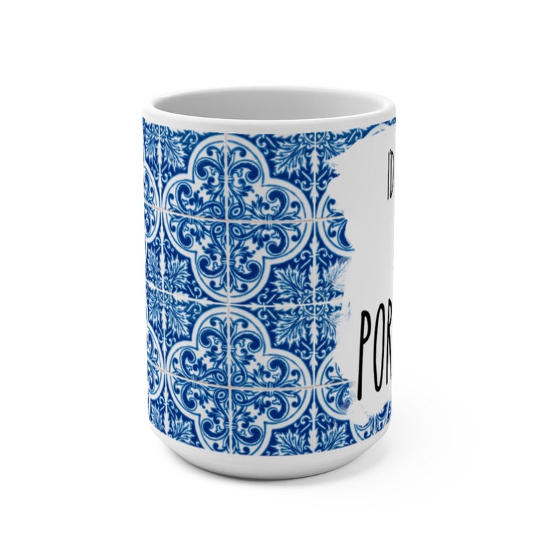 May include: White ceramic mug with a blue and white patterned design. The pattern is reminiscent of traditional Portuguese tiles. The text "I'd rather be in Portugal" is written in black on the mug.