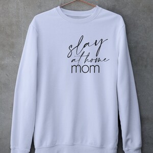 May include: White sweatshirt with black text that reads "slay at home mom".