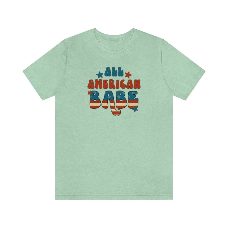 May include: A light green t-shirt with the text "All American Babe" in a retro font with red, white and blue stars and stripes.