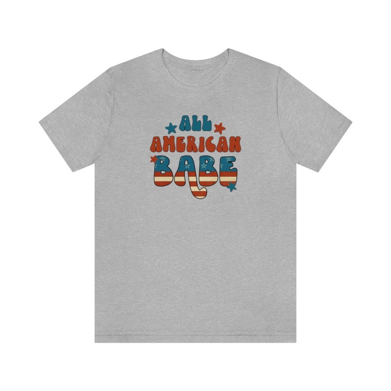 May include: A heather grey t-shirt with a retro-style graphic that says "All American Babe" in red, white, and blue with stars.