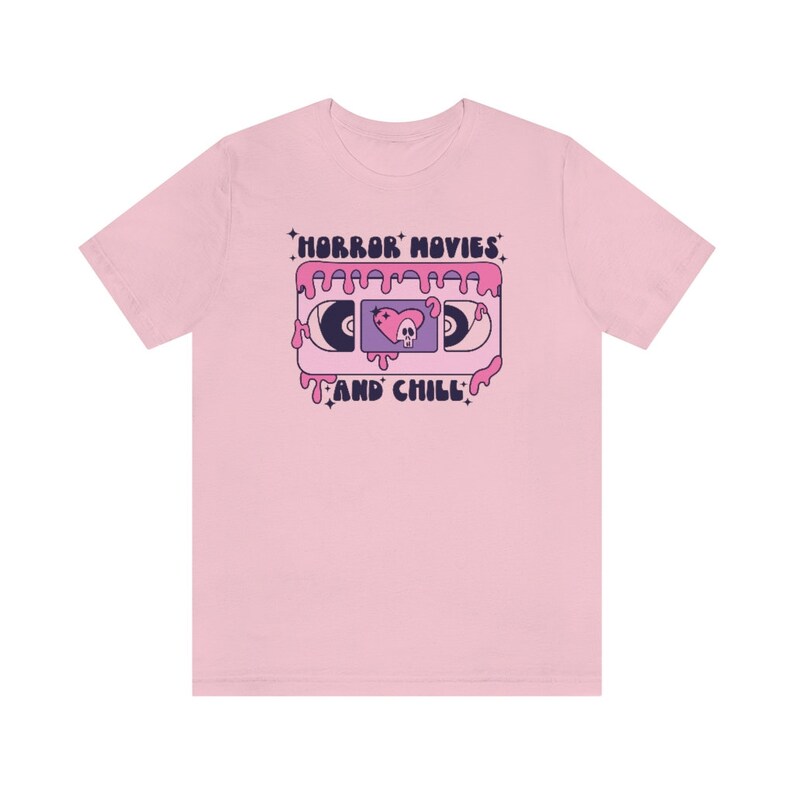 May include: Pink t-shirt with a graphic of a VHS tape dripping pink slime. The tape has a skull and heart design and the text "HORROR MOVIES AND CHILL".