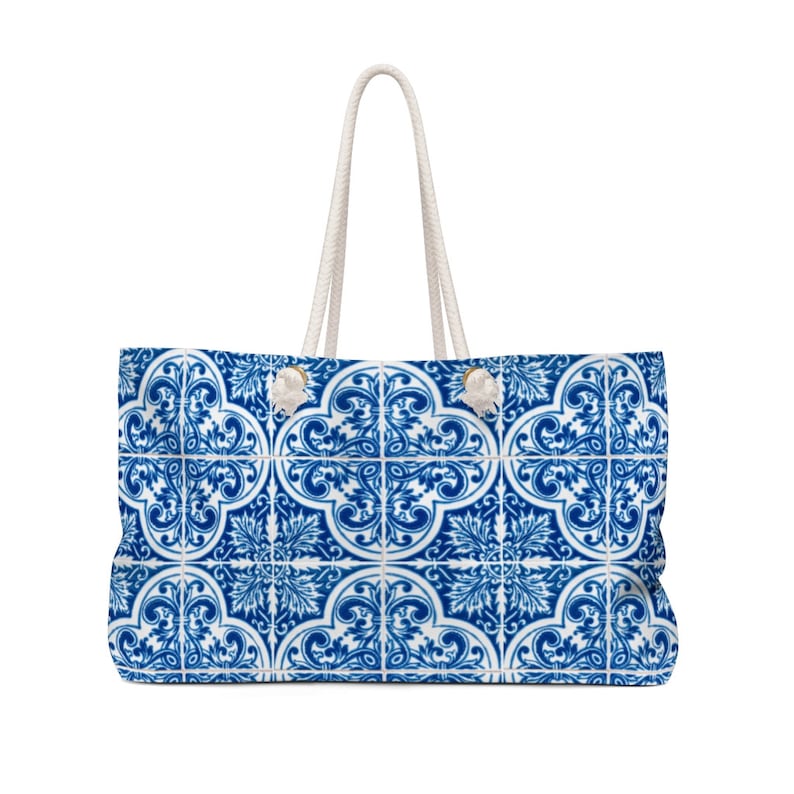 Op de afbeelding: Grote draagtas met een blauw en wit tegelpatroon. De tas heeft een rechthoekige vorm met witte touwhandvatten. Het tegelontwerp toont een herhalend bloemen- en scrollmotief, waardoor een decoratief en stijlvol accessoire ontstaat.