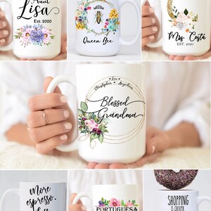 May include: A collection of white ceramic mugs with various designs and text. The mugs feature floral designs, a bee, a moon, and text such as "Aunt Lisa", "Queen Bee", "Mrs. Costa", "Blessed Grandma", "More espresso. Less depresso", "Portuguesa", and "Shopping is cheaper than therapy".
