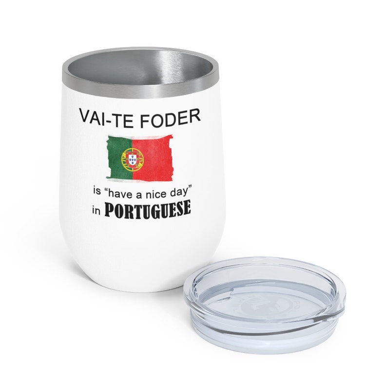 May include: White stainless steel tumbler with a silver lid. The tumbler has a black and white graphic that says "Vai-Te Foder" is "have a nice day" in Portuguese. The graphic also includes a depiction of the Portuguese flag.
