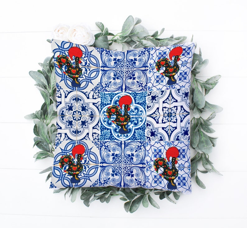 Pu&ograve; includere: Un cuscino blu e bianco con un motivo di piastrelle portoghesi con galli rossi. Il cuscino &egrave; decorato con un motivo ripetitivo di galli e forme geometriche.