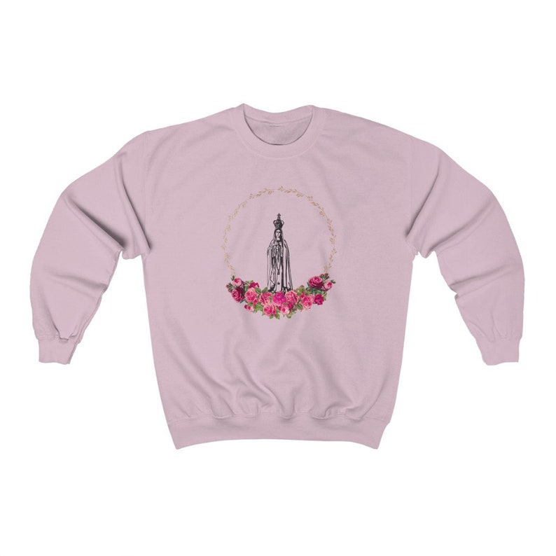Pu&ograve; includere: Una felpa rosa con una grafica di Nostra Signora di Fatima circondata da una ghirlanda di rose rosa.