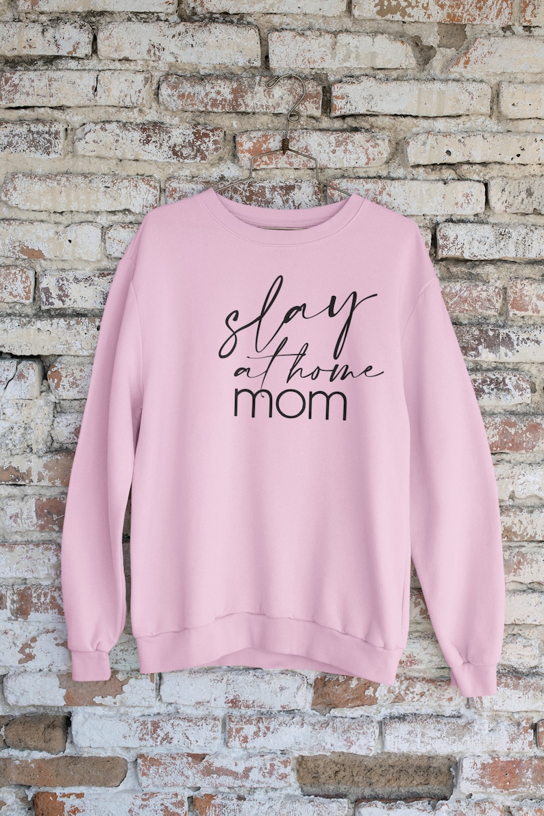 May include: Pink sweatshirt with the text "slay at home mom" in black lettering.