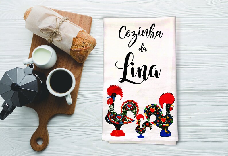 May include: White kitchen towel with the text "Cozinha da Lina" in black cursive lettering. Two colorful Portuguese roosters are depicted at the bottom of the towel.