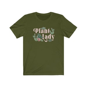 May include: A green short-sleeved t-shirt with the text "Plant Lady" in pink lettering and a floral design featuring cacti and succulents.