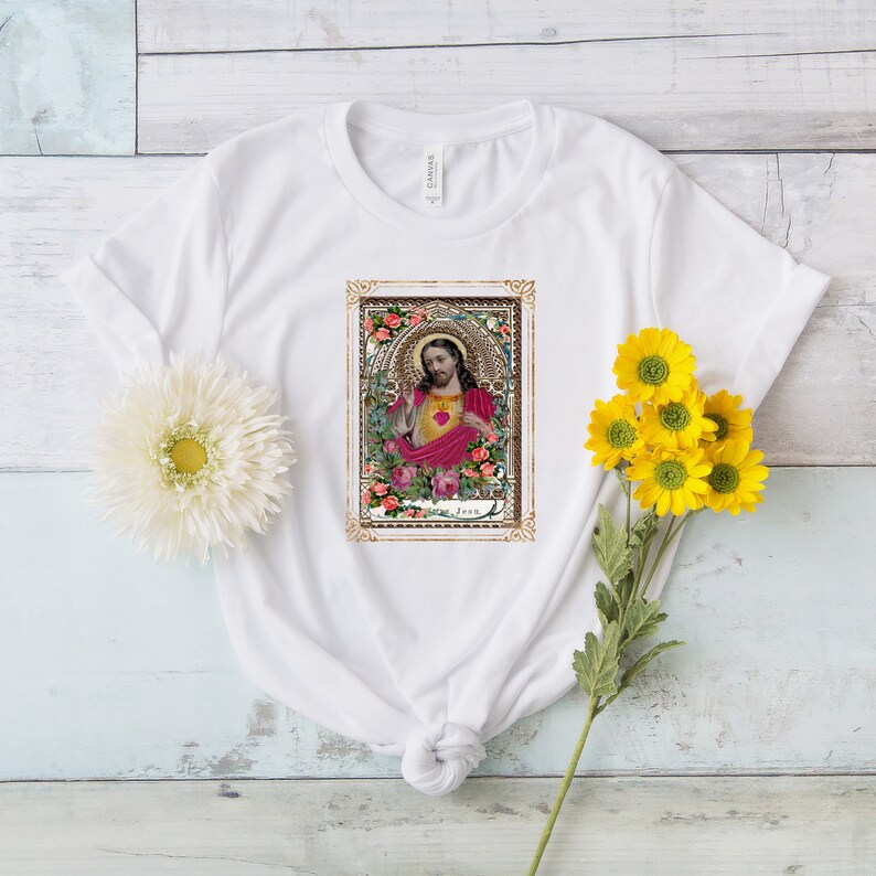 May include: White t-shirt with a vintage image of Jesus with a heart on his chest surrounded by roses in a gold frame.