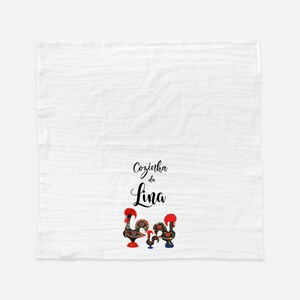 May include: White kitchen towel with black text that reads "Cozinha da Lina" and two colorful rooster illustrations.
