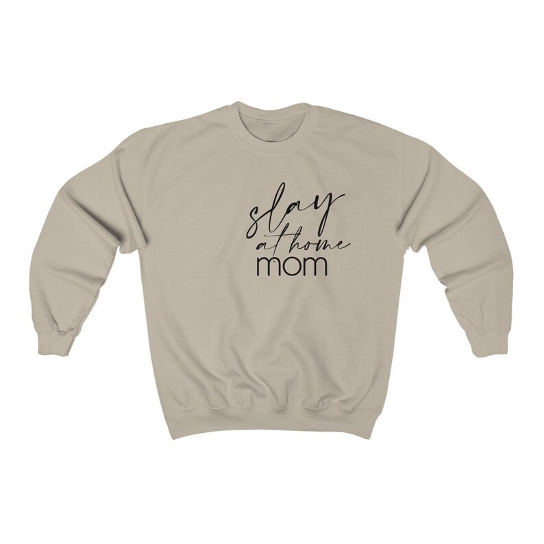 May include: A light beige sweatshirt with the text "slay at home mom" printed in black.