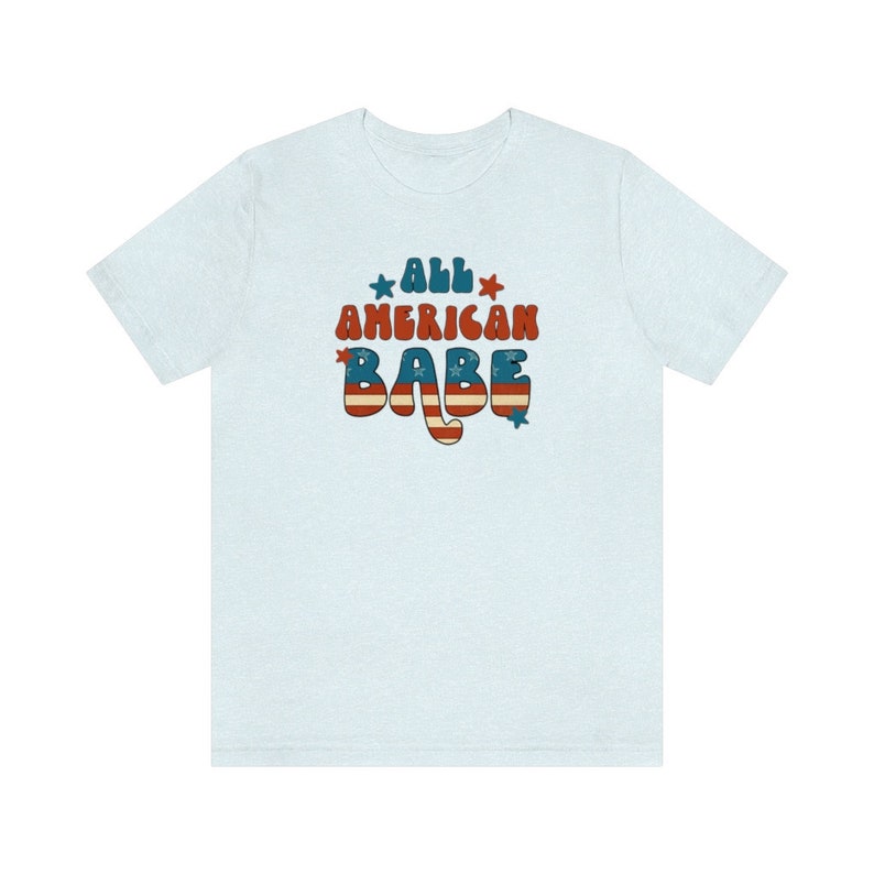 May include: Light blue t-shirt with a retro-style graphic that says "All American Babe" in red, white and blue with stars.