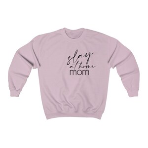 May include: A light pink sweatshirt with the text "slay at home mom" in black script.