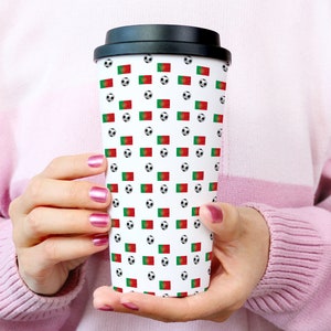 May include: A white travel mug with a black lid and a pattern of soccer balls and the Portuguese flag.