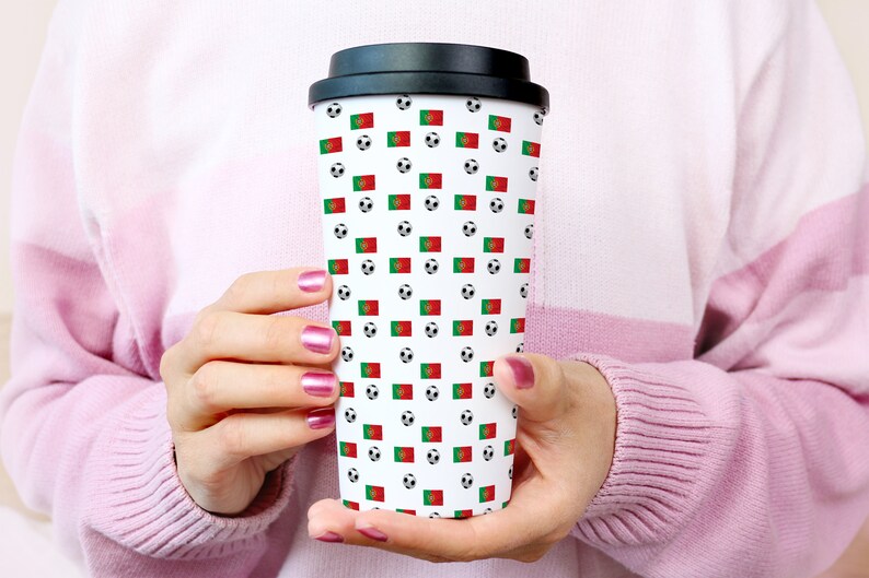 May include: A white travel mug with a black lid and a pattern of soccer balls and the Portuguese flag.