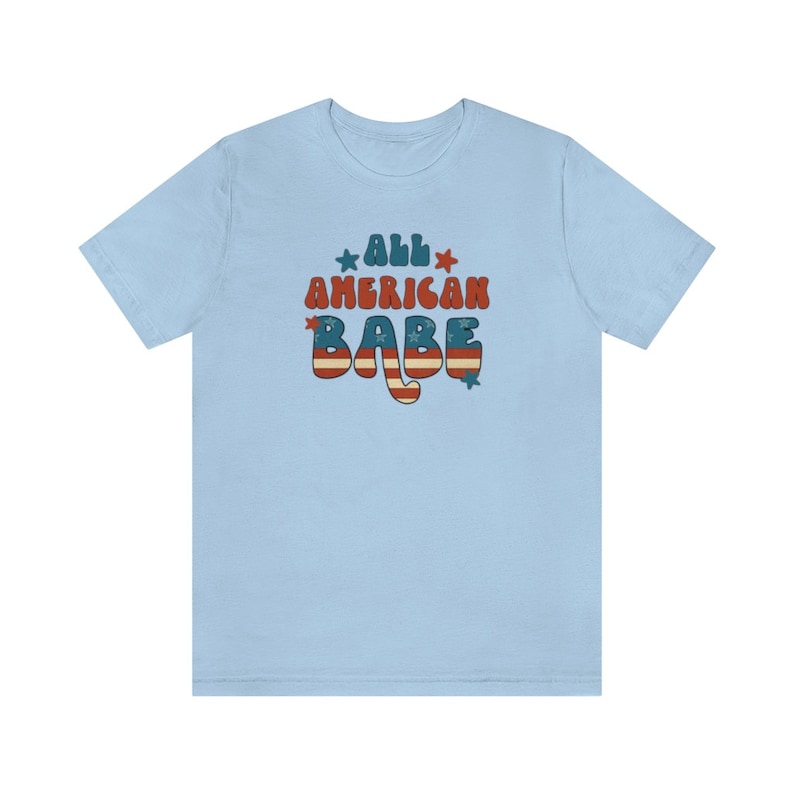 May include: Light blue t-shirt with a retro-style graphic that says "All American Babe" in red, white and blue with stars.